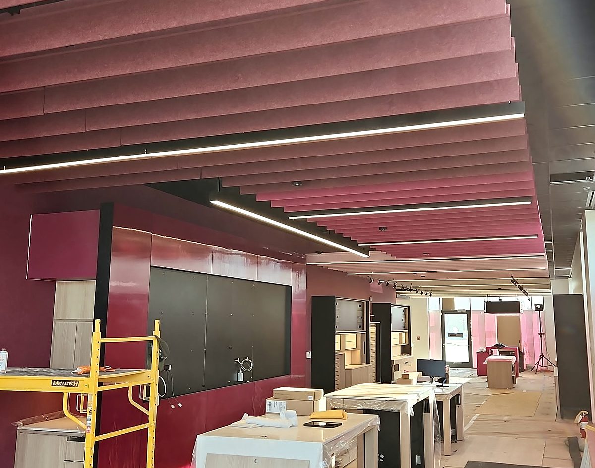 T-Mobile retail store interior during fit-out — ceiling baffles and feature wall complete